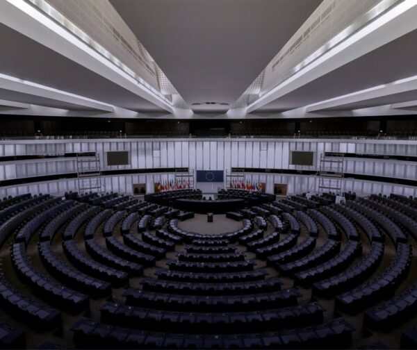 Empty government building with circular seating arrangement and European Union flags.