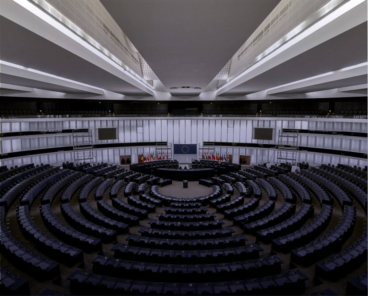 Empty government building with circular seating arrangement and European Union flags.