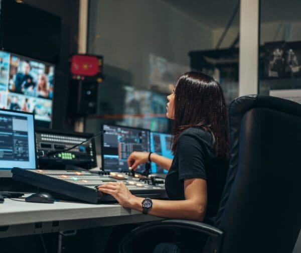 Person operating a broadcast camera control panel in a production control room.
