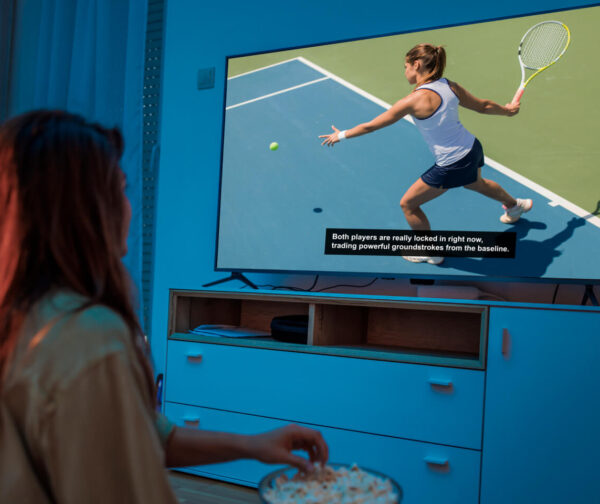 Person watching a tennis match on TV with LEXI Automatic Captions displayed