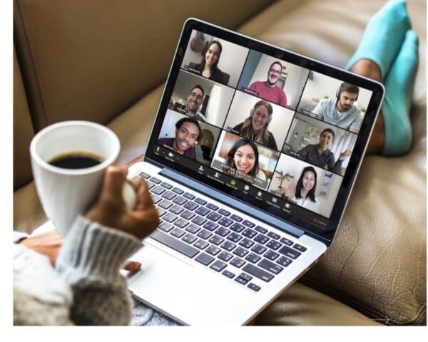 Person holding a coffee cup while attending a virtual meeting on a laptop, with captions on the screen for accessibility.